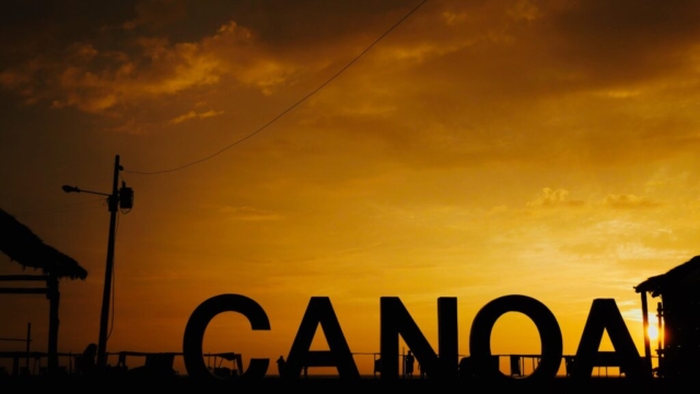 The sun sets behind the letters on the beach